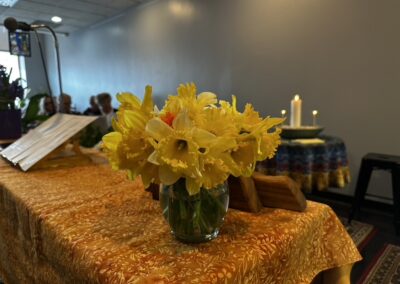 A vase of yellow daffodils on the altar table beside a lit candle