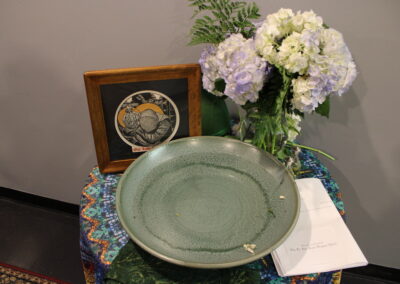Table display with a ceramic bowl, flowers, and framed artwork
